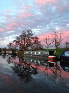 Reflection of narrowboats under a pink and blue twilight sky on the Lancaster canal